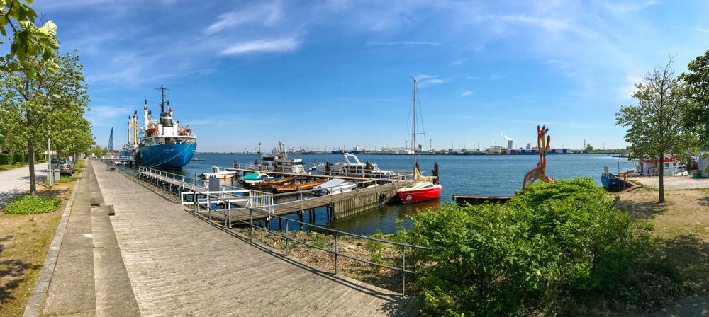 Panorama von Promenade IGA Park. Boote im Vordergrund. Frachtschiff Likedeeler und Hafenanlagen im Hintergrund 