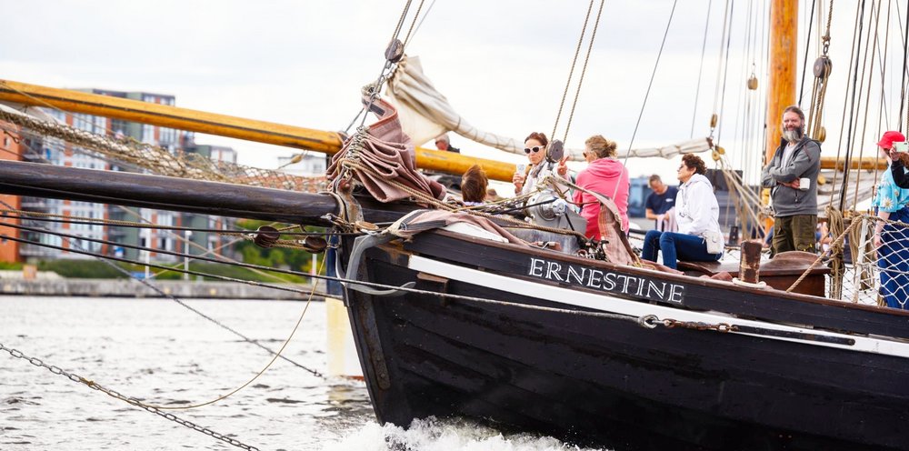 Das Segelschiff "Ernestine" fährt mit mehreren Personen an Bord, die die Fahrt genießen.